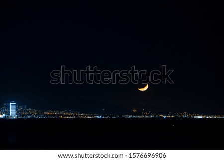 Moon set and city lights at night. 