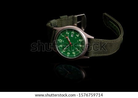 watch with green clock face and green strap on black background