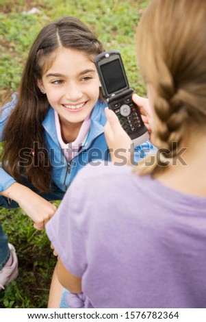 Two young friends taking pictures with their mobile phone