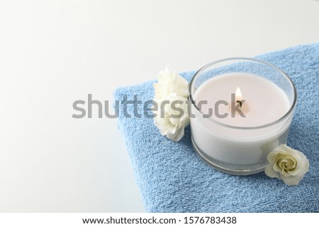 Towel, candle and eustoma on white background, copy space. Spa concept