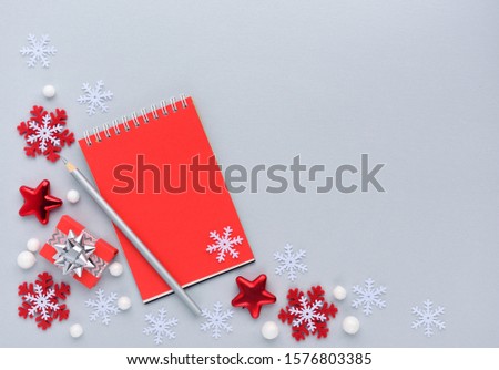 Christmas or New Year greeting card. The notebook with the pencil and christmas decorations on gray background. Flat lay, top view, copy space