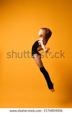 Young sport woman gymnastics doing jumping fitness exercise at sport gym jump on yellow background