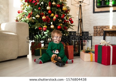 boy playing with toy train and gift boxes and christmas tree on background