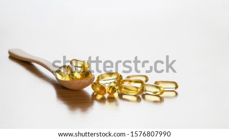 Fish oil capsules with omega3 and vitamin D in wooden spoon on wooden table background,benefits supplement and support heart health,healthy diet concept, selective focus