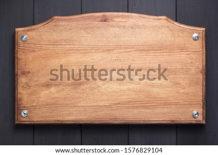 wooden nameplate at black background texture surface with screws
