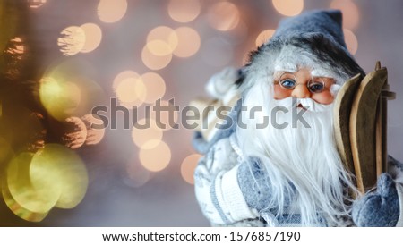 Beautiful santa claus in glasses with skis and gifts on bokeh lights background. 