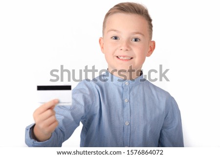 blonde caucasian cute boy in blue shirt holding credit card.picture isolated on white background.