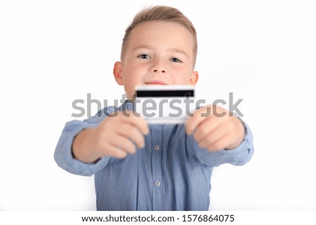 blonde caucasian cute boy in blue shirt holding credit card.picture isolated on white background.