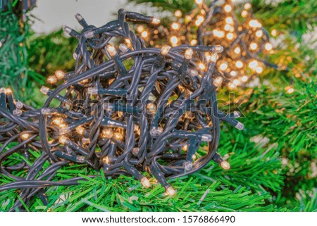Christmas tree indoors fairy lights ball illuminating. A series of low voltage string festive LED lights on a dark green cable with light effect & bokeh defocused warm lights background.