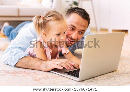 Education Concept. Millennial dad teaching his daughter how to use laptop. Free space