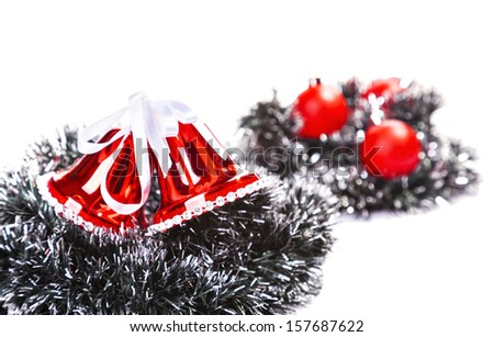 two red Christmas bells are in the tinsel on a white background