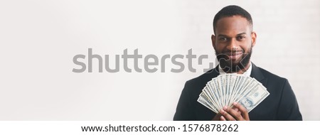 Young successful black businessman holding dollars over white background, panorama with copy space