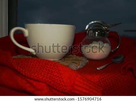 A mug of tea with lemon on a beautiful red background on a wooden stand.