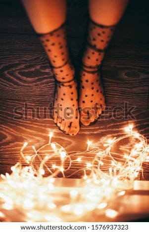 Female legs in socks with stars and christmas lights. On the eve of the holiday