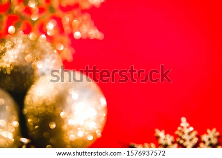 Blurred defocused red Christmas and New Year's background with golden baulbes and snowflakes. Holiday mood concept.