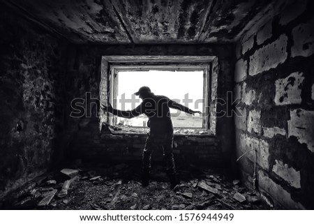 man against the background of a window in a ruined house, horror, fear concept, radiation stalker in Chernobyl zombie apocalypse