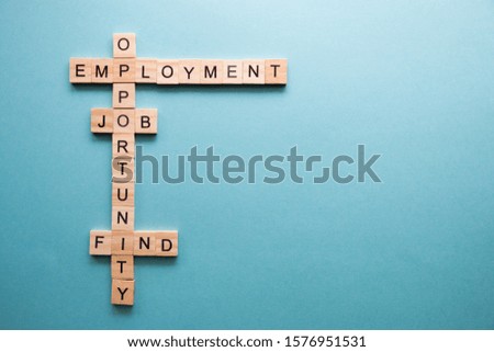 words related to work, to job search are collected in a crossword puzzle with wooden cubes on a blue background.