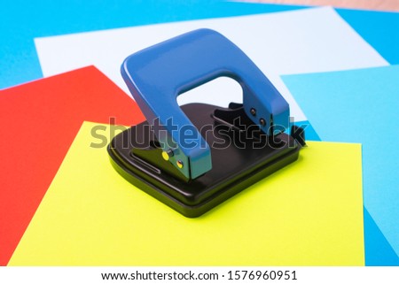 Puncher and sheets of colored paper close-up.