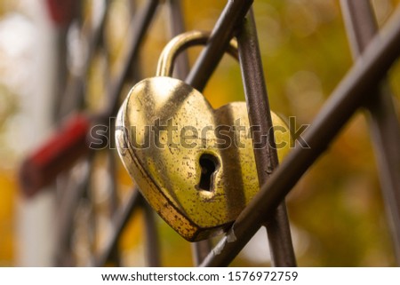 Golden heartshaped padlock. Abraded and shabby love lock with a keyhole