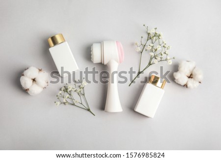 Flat lay composition with face cleansing brush on light grey background. Cosmetic accessory