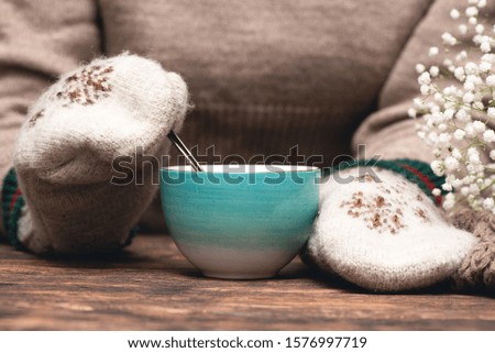 Woman in warm sweater and mittens is drinking a hot tea close up background.