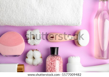 Flat lay composition with face cleansing brushes on violet background. Cosmetic tools