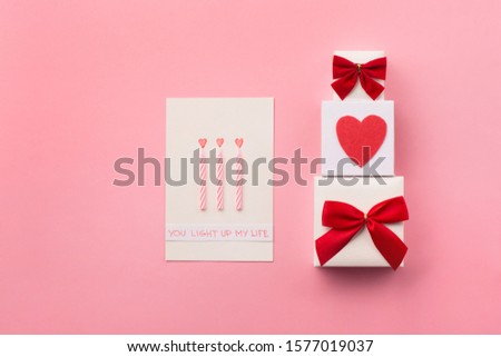 Valentines day, birhtday, wedding or other holiday composition. Handmade wrapped gift boxes, red hearts and candles on pink background. Copy space for text. Flat lay
