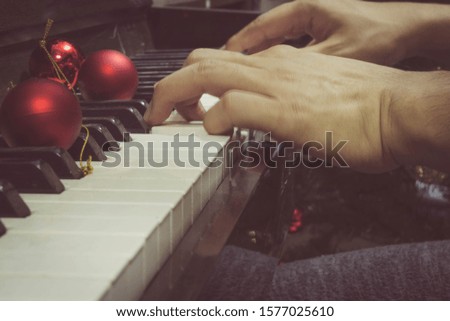 Red christmas tree decoration ball Put on the piano And a moving hand playing the piano To celebrate the Christmas season or New Year