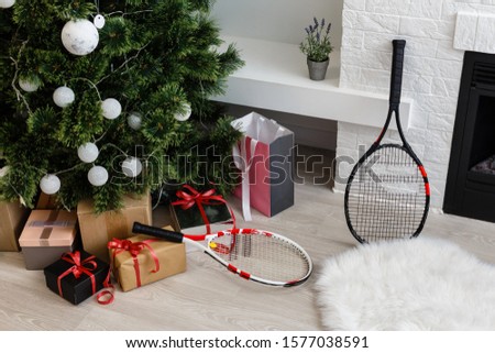 gifts and a tennis racket lie near a Christmas tree