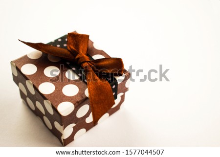 Christmas present with a bow lies on a white table. A small gift on a white background. Merry Christmas