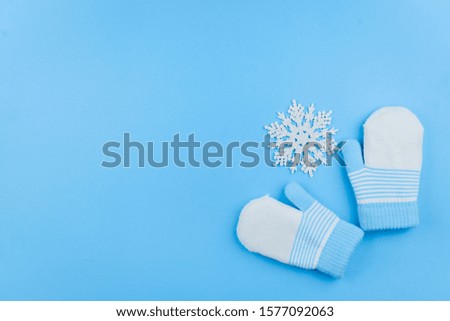 Woolen mittens with Christmas toys on a blue background. Winter concept. Close-up with space for text.
