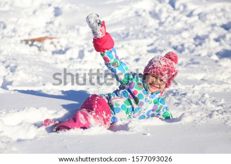 little girl playing on snow in winter time