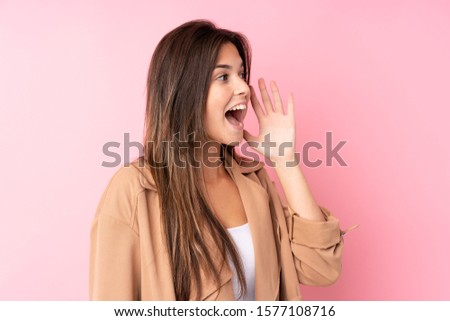 Teenager Brazilian girl over isolated pink background shouting with mouth wide open