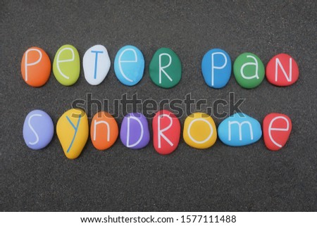 Peter Pan syndrome, inability to grow up in behaviour usually associated with adulthood, phrase composed with colored stone letters over volcanic sand