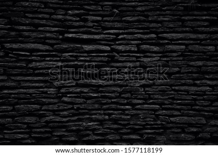 Black background. Old weathered natural sandstone wall. Black and white photo.