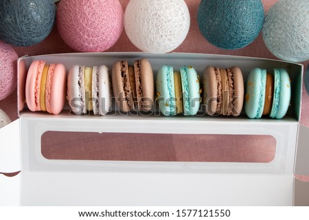 Macarons with cream in a festive open box near the holidays decorations. Top view.