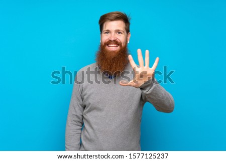 Redhead man with long beard over isolated blue background counting five with fingers