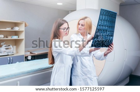 Two beautiful model girls doctors examine MRI picture