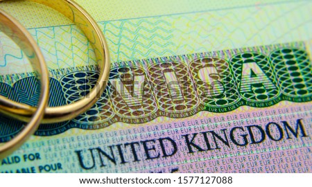 UK entry visa sticker in a passport and the rings placed on top. Concept for Partner and Spouse visa UK.  Royalty-Free Stock Photo #1577127088
