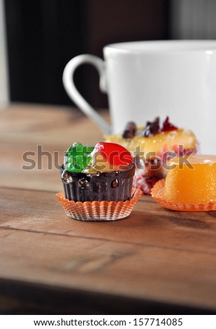 small sweet cakes with cup of coffee on wooden table