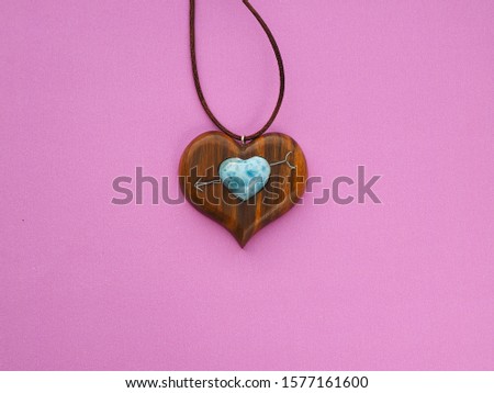 heart pendant made of bacout tree and larimar stone. pink background.