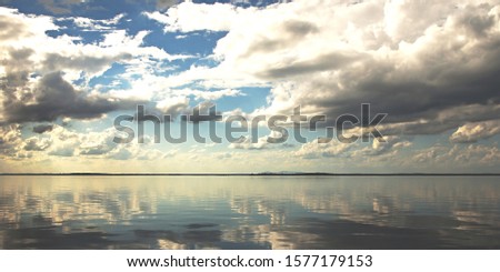 Nephology at its best. A beautiful meteorological sky cloudscape scene, with white Cumulus cloud formation in a light blue sky with ocean water reflection. New South Wales, Australia.