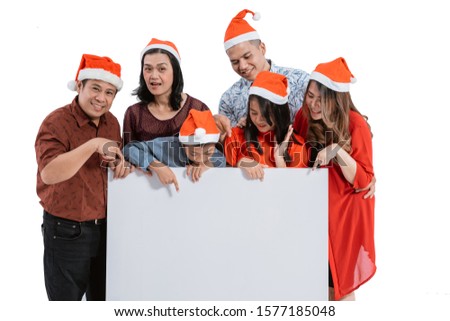 portrait of family with santa claus hat smiling holding blank board