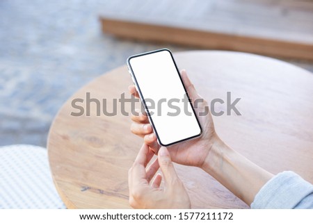 Mockup image blank white screen cell phone.man hand holding texting using mobile on desk coffee shop or cafe.background empty space for advertise text.people contact marketing business and technology 