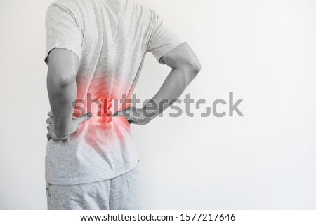 Office syndrome, Backache and Lower Back Pain Concept. a man touching his lower back at pain point Royalty-Free Stock Photo #1577217646