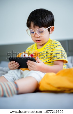 little kid boy using digital tablet or smart phones for playing games and watching cartoons, smart phone mobile addiction technology communication lifestyles.