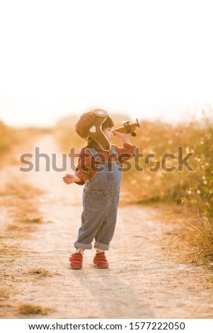 Child pilot aviator with airplane dreams of traveling in summer in nature at sunset