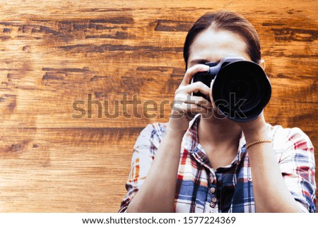 Woman photographer is taking images with digital camera on old wooden background