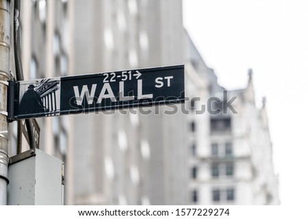 Wall street sign in New York city financial economy and business district with building and sky background. Stock market trade and exchange zone.