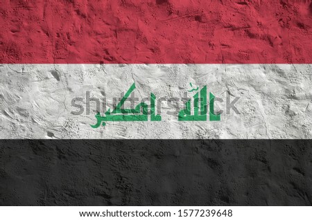 Iraq flag depicted in bright paint colors on old relief plastering wall. Textured banner on rough background